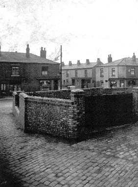 Entrance to Victoria Street and corner shops, seen from the yard of Yates's mill.